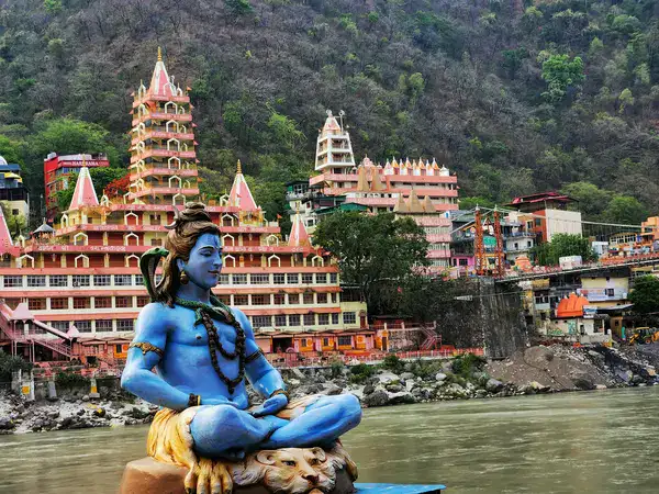 Statue of a person with a cobra on the shoulder and the Trayambakeshwar Temple in the background